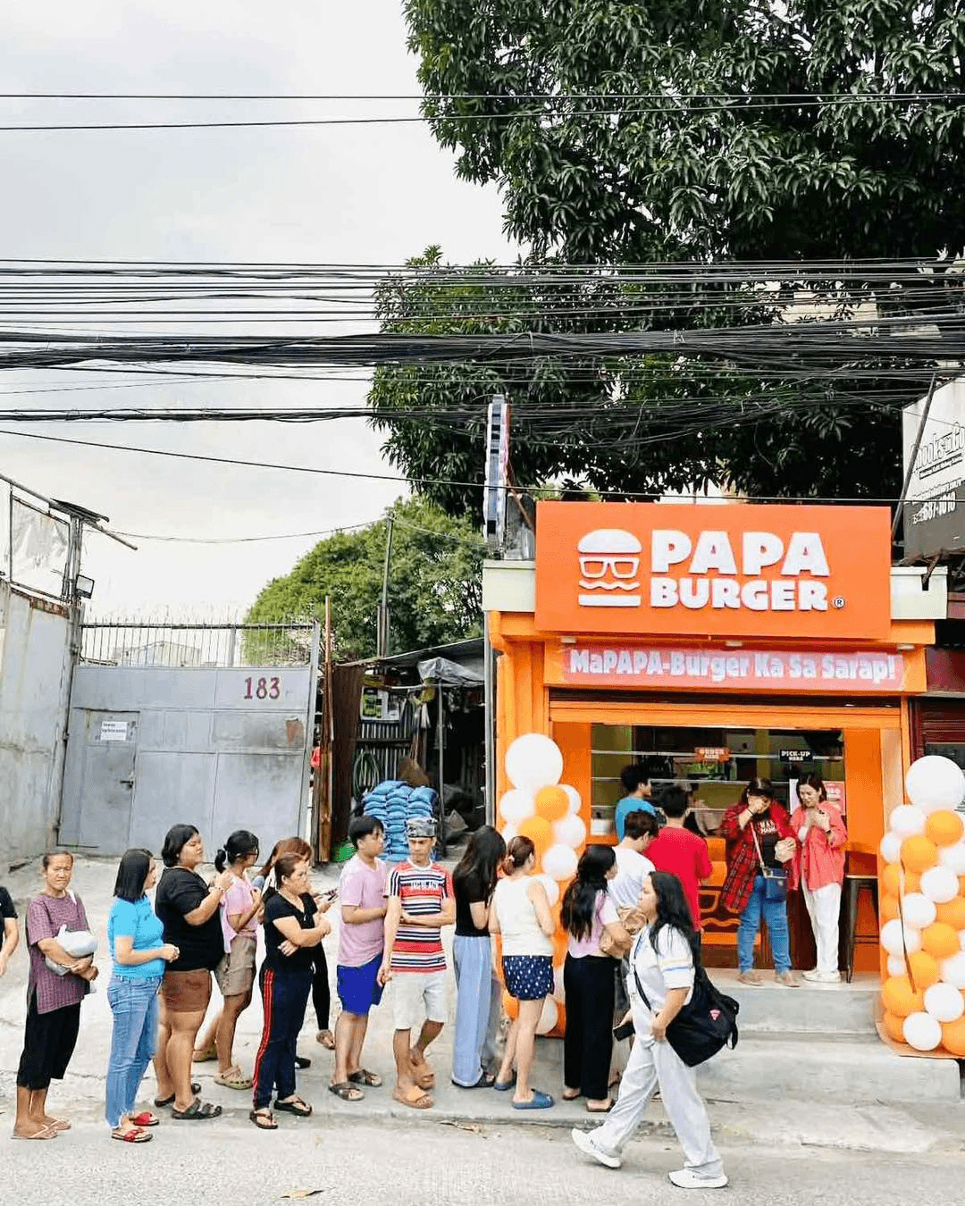 Customers queuing on the pavement outside a Papa Burger branch.