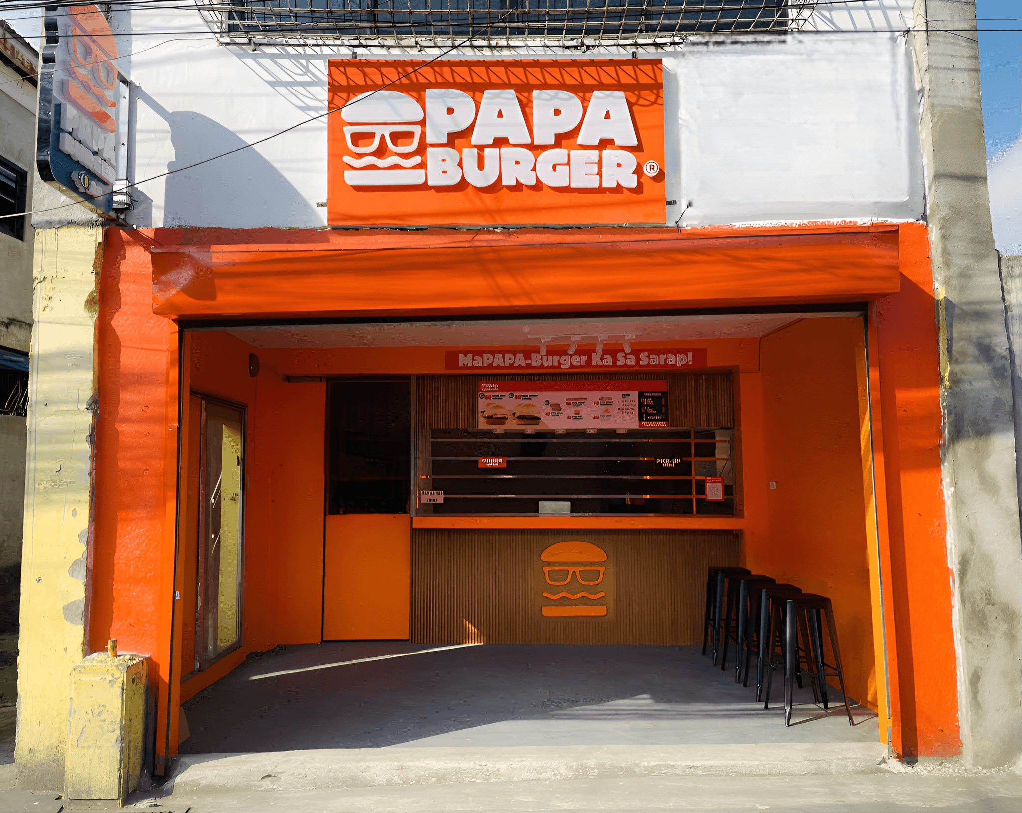 A Papa Burger branch open to the street, its counter and signage visible from the pavement.
