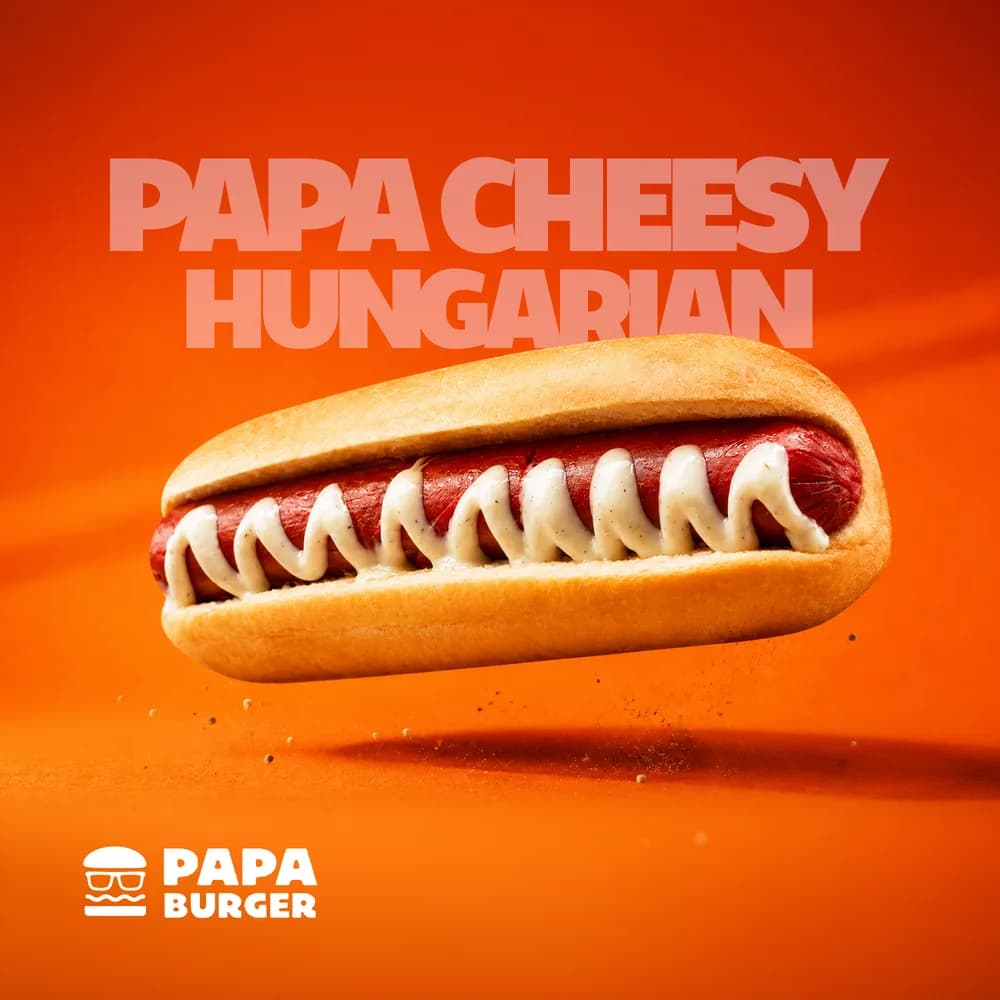 A Papa Cheesy Hungarian sausage in a bun under a zigzag of cheese sauce.